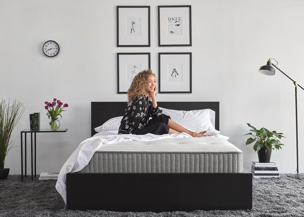 Smiling woman sitting on a charcoal-infused memory foam mattress